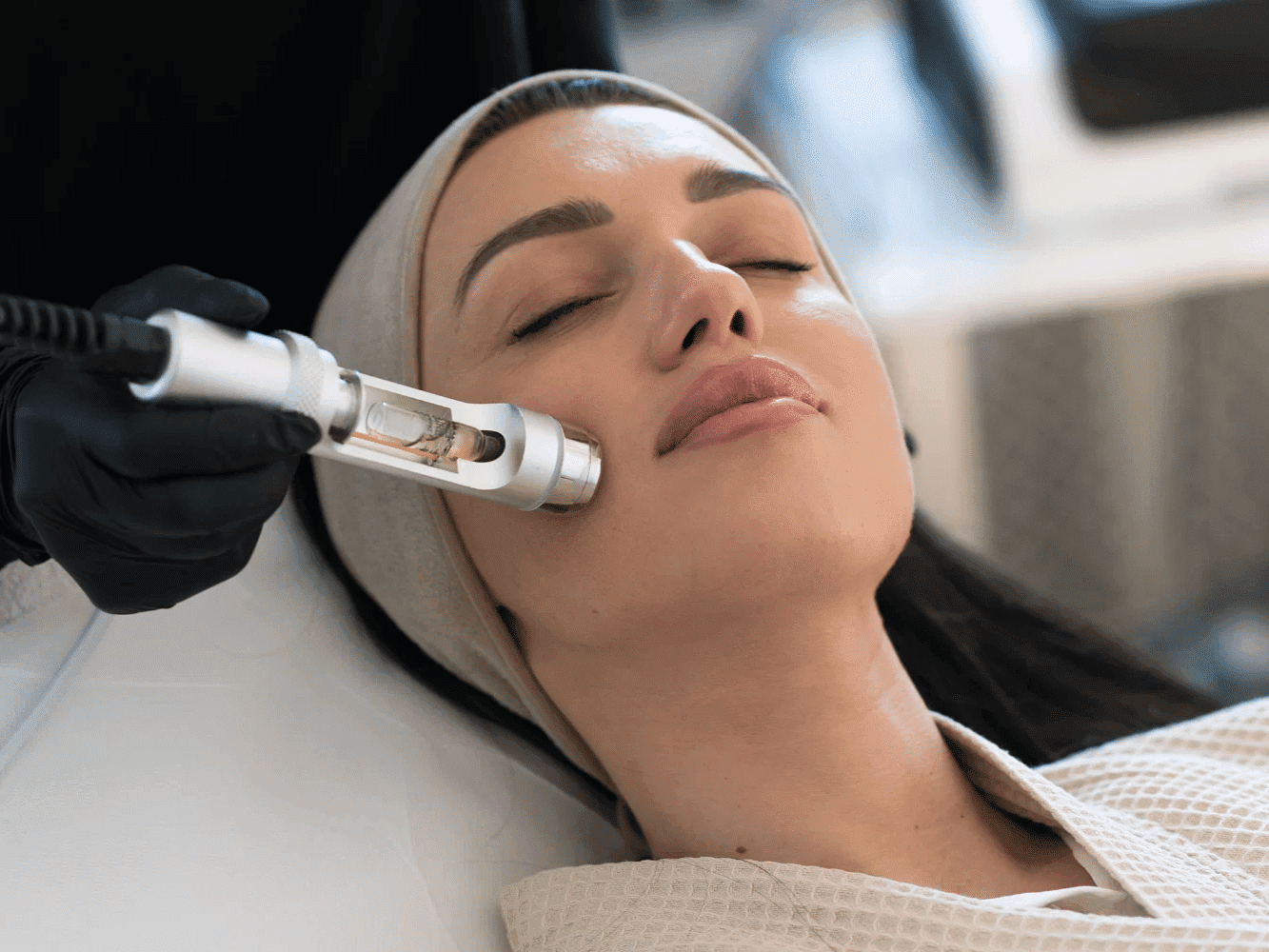 Woman undergoing facial treatment with a skincare tool.