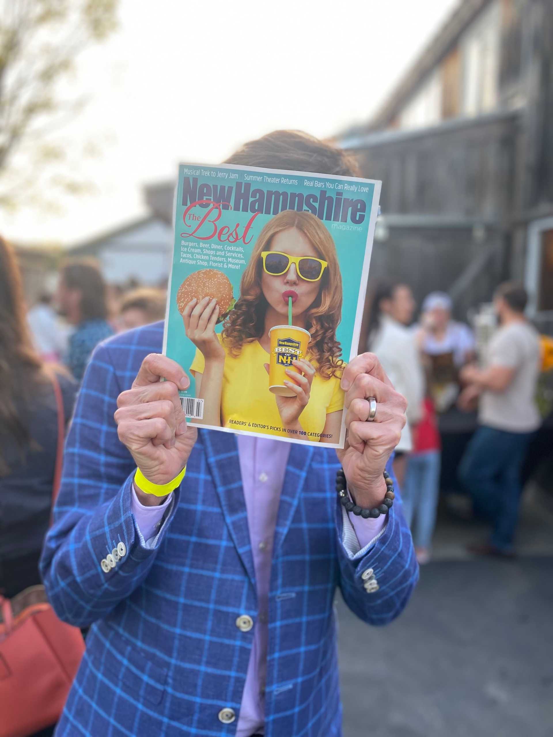Person holding a magazine cover in front of their face; the cover features a woman with sunglasses.