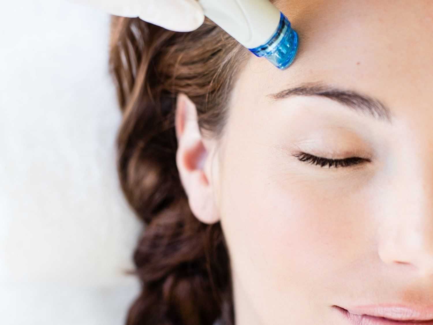 Hydrofacial treatment applied to woman's forehead.
