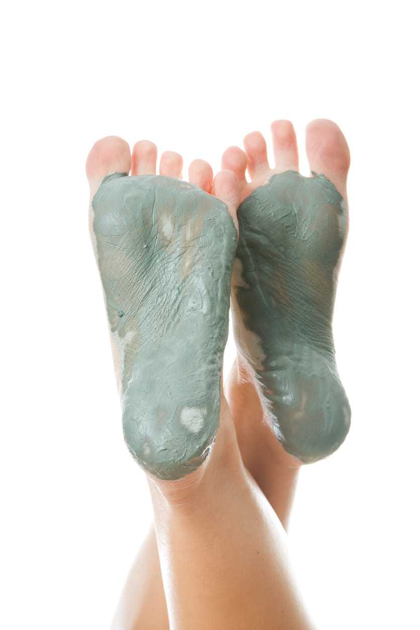 Feet with green clay mask applied on soles, suggesting a spa or skincare treatment.