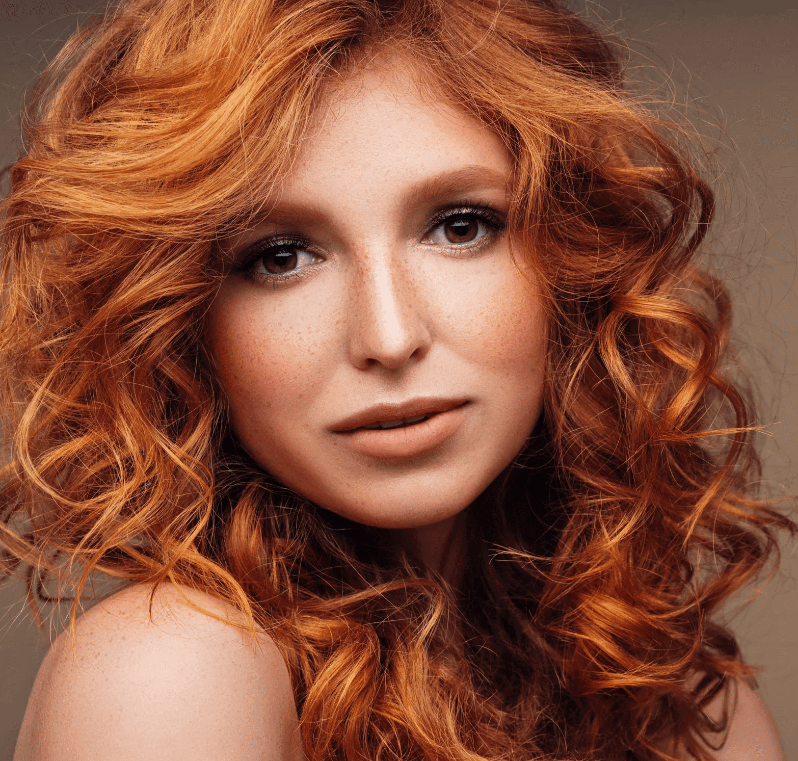 Red-haired person with curly hair gazes intently, set against a neutral background.